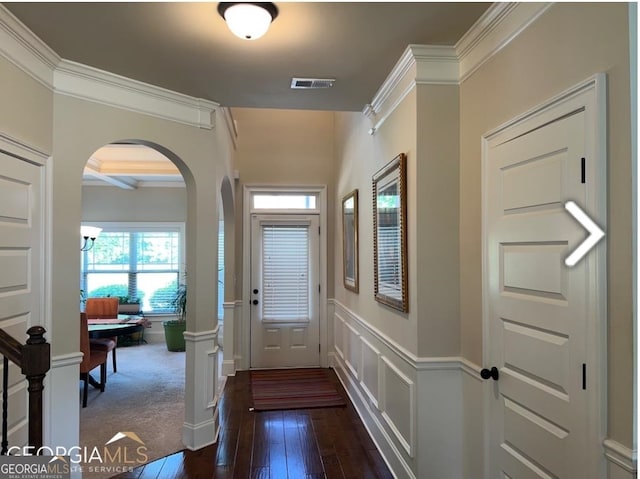 entryway with ornamental molding and dark carpet