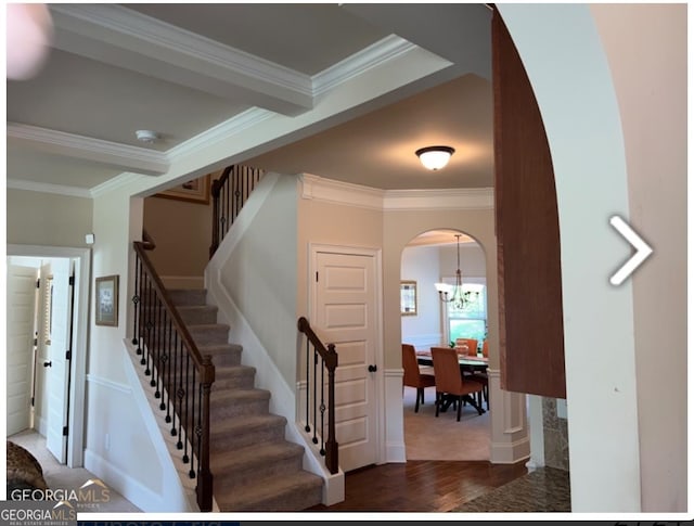 stairway featuring a chandelier, crown molding, and dark hardwood / wood-style floors