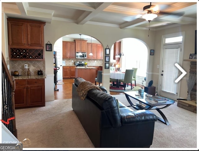 living room with light colored carpet, ceiling fan, crown molding, beam ceiling, and coffered ceiling