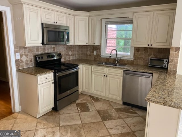 kitchen with backsplash, sink, stainless steel appliances, and light tile floors