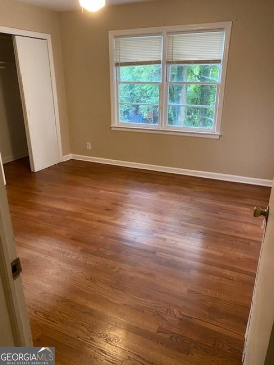 unfurnished bedroom featuring a closet and dark hardwood / wood-style floors