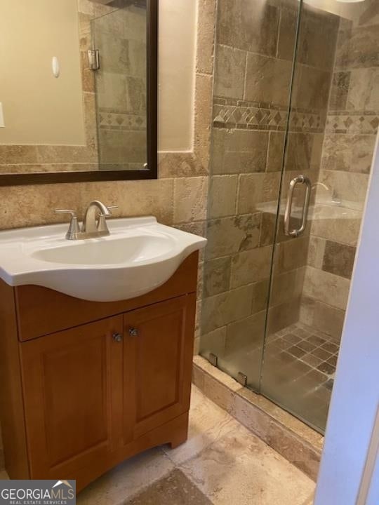 bathroom with walk in shower, tasteful backsplash, vanity, and tile walls