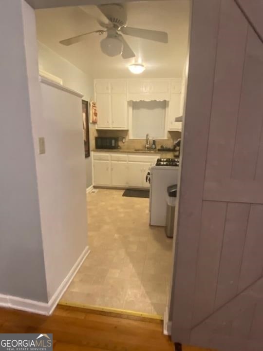 kitchen with ceiling fan, sink, white cabinetry, stove, and tile floors