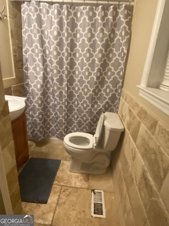 bathroom with tile walls, toilet, tile floors, and vanity