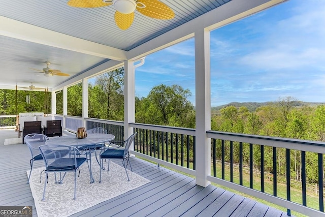 wooden terrace with an outdoor living space and ceiling fan