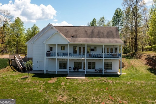 rear view of house with a balcony, a lawn, and a patio area