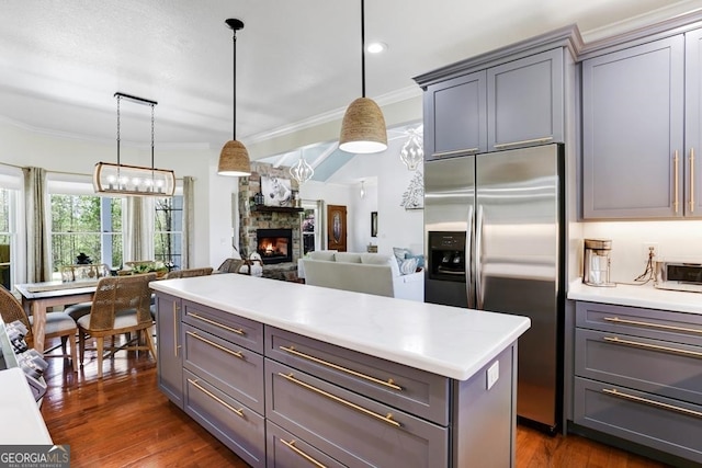 kitchen with hanging light fixtures, stainless steel refrigerator with ice dispenser, a fireplace, gray cabinets, and dark hardwood / wood-style flooring