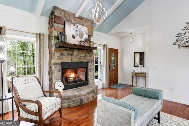 living room with beamed ceiling, hardwood / wood-style floors, a stone fireplace, and a healthy amount of sunlight