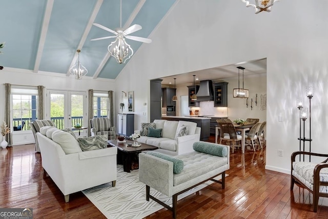 living room with beamed ceiling, high vaulted ceiling, ceiling fan with notable chandelier, hardwood / wood-style floors, and french doors