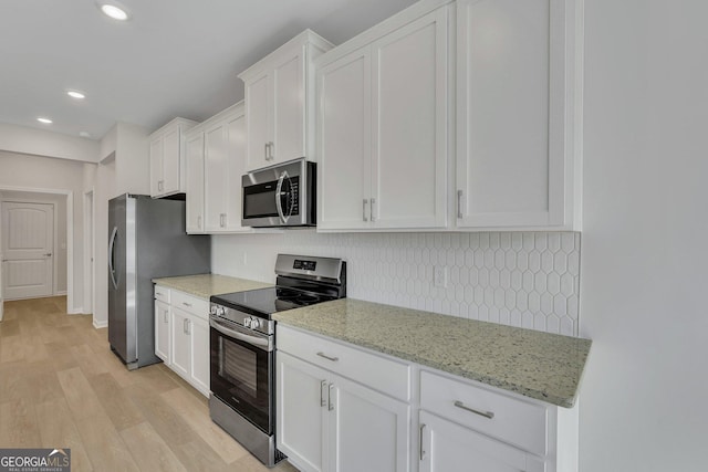 kitchen with stainless steel appliances, light stone countertops, light hardwood / wood-style floors, and white cabinets