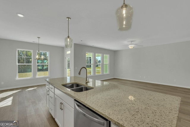 kitchen with white cabinetry, an island with sink, sink, stainless steel dishwasher, and light stone counters