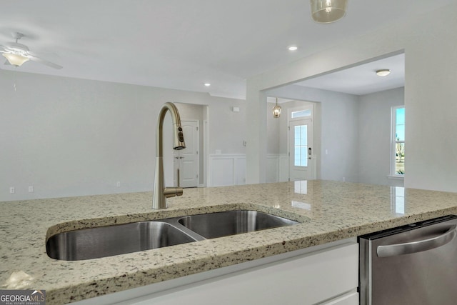 kitchen featuring decorative light fixtures, dishwasher, sink, and light stone countertops