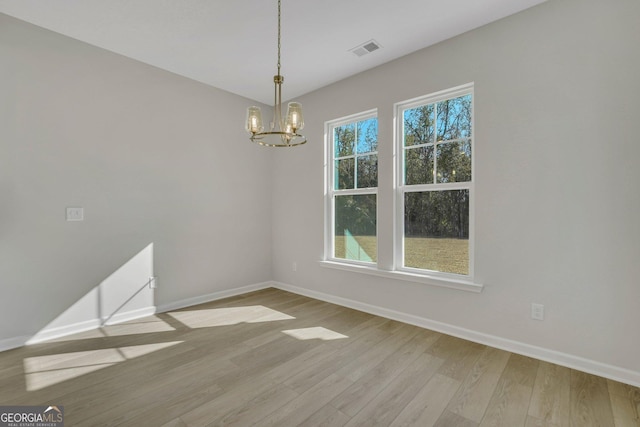 unfurnished dining area featuring a healthy amount of sunlight, a chandelier, and light hardwood / wood-style floors