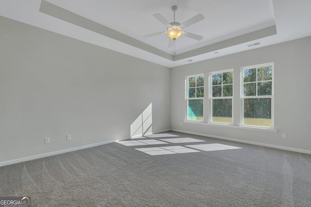 carpeted empty room with a raised ceiling and ceiling fan