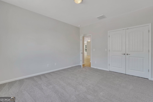 unfurnished bedroom featuring light carpet and a closet