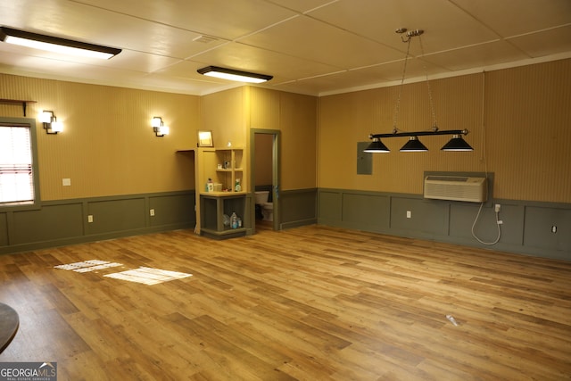 spare room with a wall mounted AC, electric panel, and hardwood / wood-style flooring