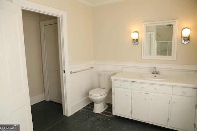 bathroom featuring vanity, toilet, a shower with shower door, and ornamental molding