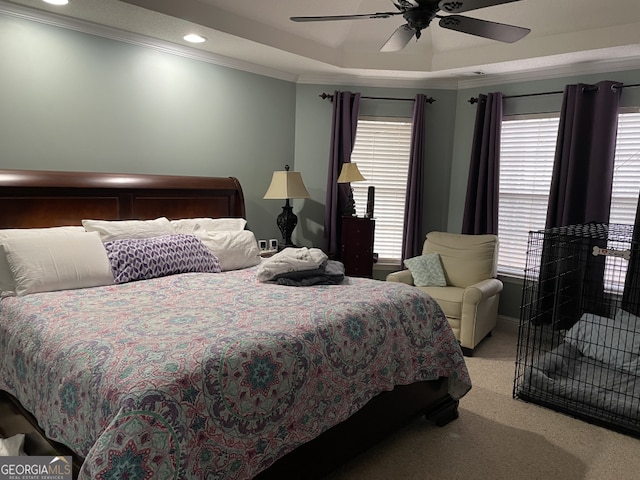 bedroom with a tray ceiling, crown molding, light colored carpet, and ceiling fan