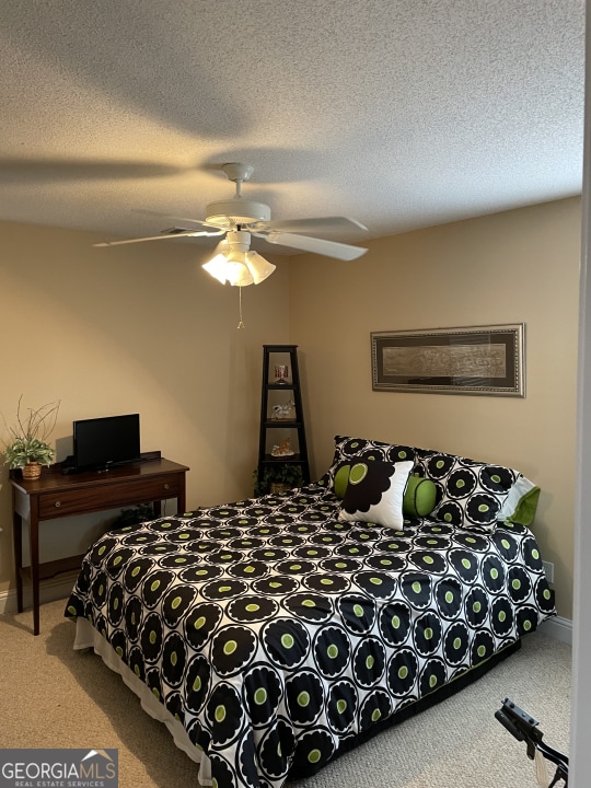 bedroom with ceiling fan, carpet flooring, and a textured ceiling