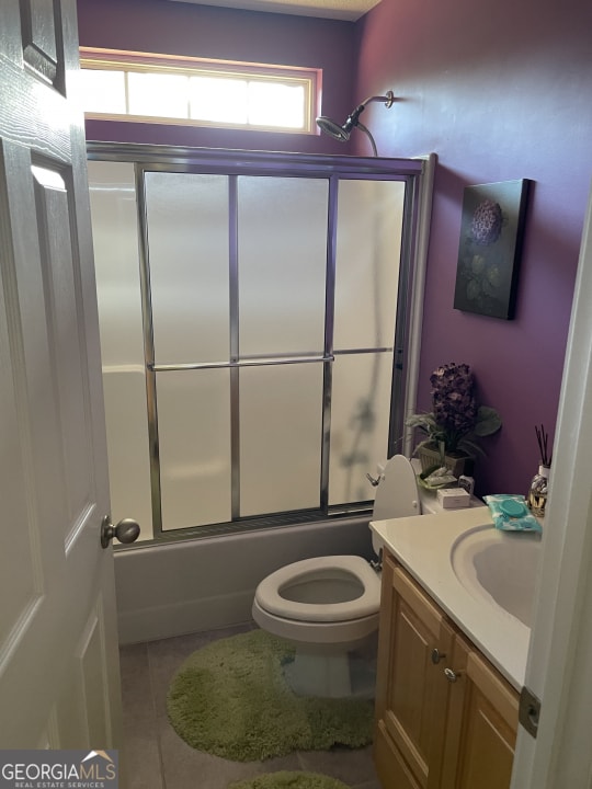 full bathroom featuring tile patterned flooring, vanity, toilet, and combined bath / shower with glass door