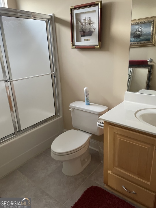 full bathroom featuring tile patterned flooring, bath / shower combo with glass door, vanity, and toilet