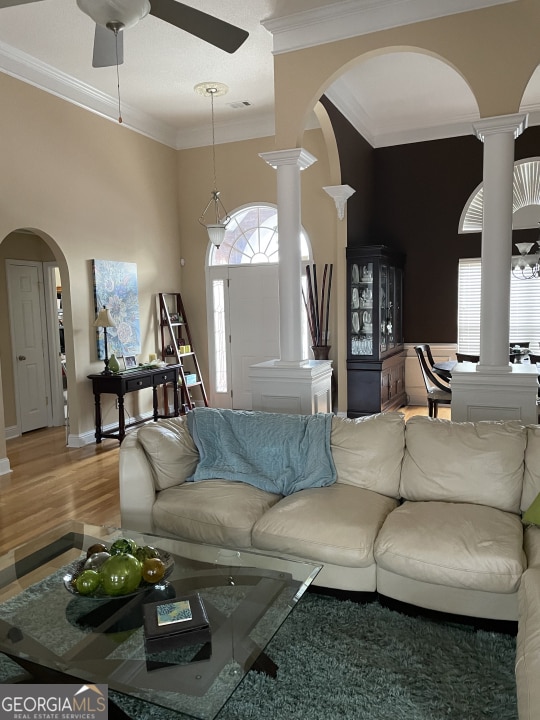 living room with ceiling fan, ornamental molding, wood-type flooring, and ornate columns