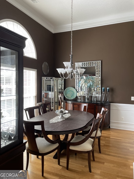 dining area featuring crown molding, light hardwood / wood-style flooring, and a chandelier