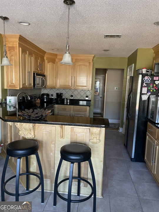 kitchen with stainless steel appliances, a breakfast bar area, pendant lighting, and kitchen peninsula