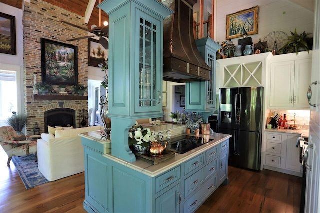 kitchen with ceiling fan, premium range hood, black appliances, dark hardwood / wood-style floors, and a large fireplace