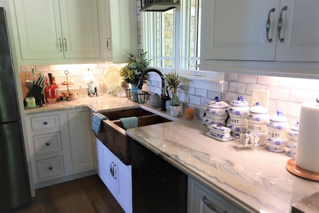 kitchen featuring decorative backsplash, white cabinets, light stone counters, and fridge