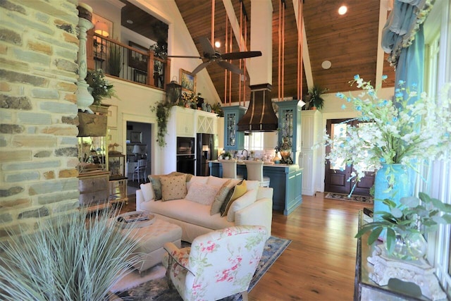 living room featuring light hardwood / wood-style floors, high vaulted ceiling, wooden ceiling, ceiling fan, and sink