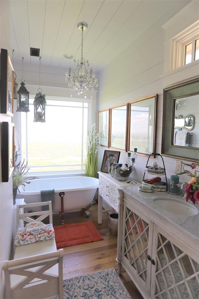 bathroom with vanity, a bathing tub, a chandelier, and hardwood / wood-style floors