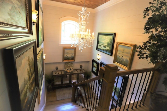 stairway featuring an inviting chandelier, crown molding, and hardwood / wood-style floors