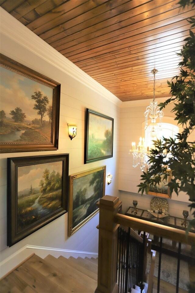 hall featuring hardwood / wood-style flooring, a chandelier, ornamental molding, and wooden ceiling