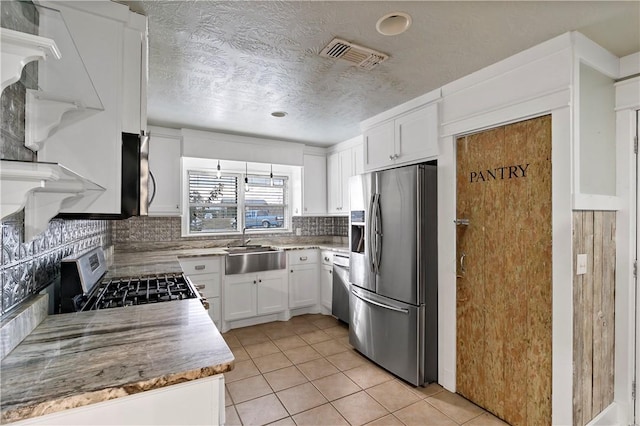 kitchen featuring backsplash, white cabinets, sink, light tile patterned floors, and appliances with stainless steel finishes