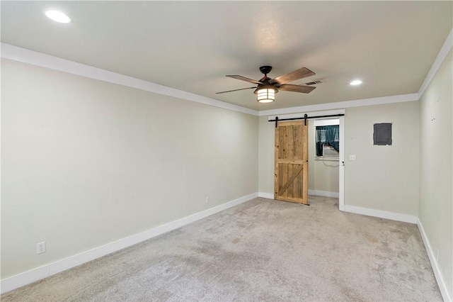 unfurnished bedroom featuring a barn door, crown molding, ceiling fan, and light colored carpet