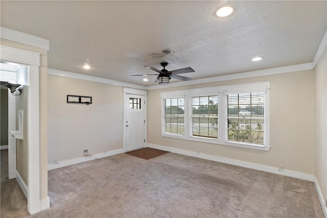 carpeted foyer entrance with ceiling fan and ornamental molding