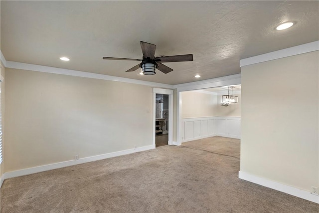 carpeted spare room featuring a textured ceiling, ceiling fan with notable chandelier, and ornamental molding