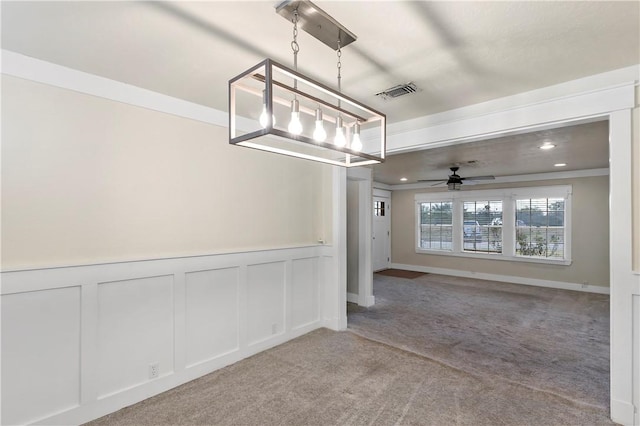 unfurnished dining area featuring light colored carpet, ceiling fan, and crown molding