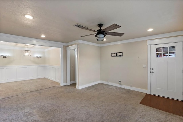 entrance foyer featuring light carpet, ceiling fan, and ornamental molding