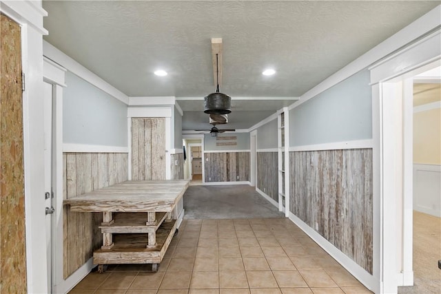 interior space featuring wood walls, light colored carpet, and a textured ceiling