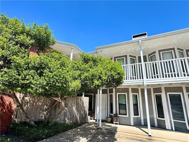 back of house with a balcony, a chimney, and fence