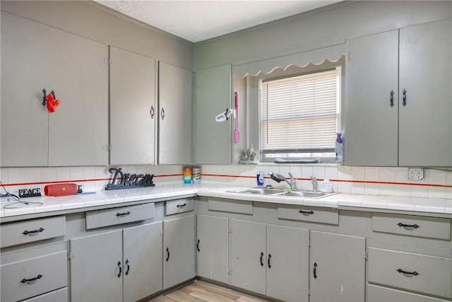 kitchen with backsplash, tile countertops, and sink