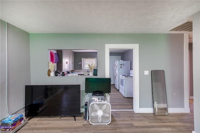 kitchen featuring electric range, light hardwood / wood-style floors, and a textured ceiling