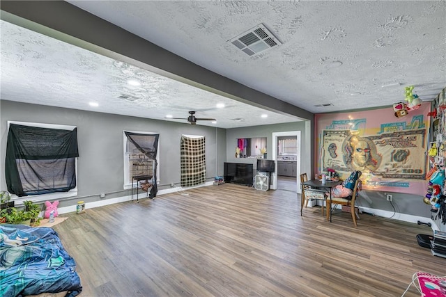 sitting room featuring hardwood / wood-style flooring, ceiling fan, beam ceiling, and a textured ceiling