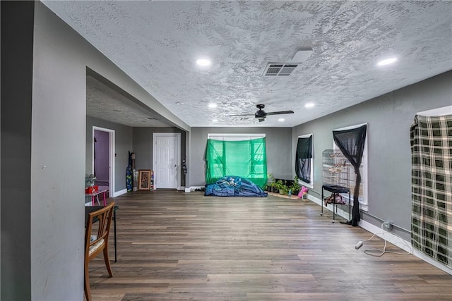 exercise area featuring ceiling fan, wood-type flooring, and a textured ceiling