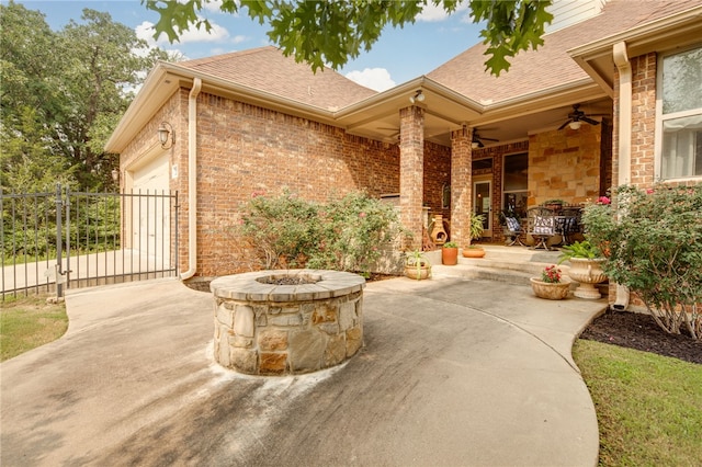 view of patio / terrace with ceiling fan, a garage, and an outdoor fire pit