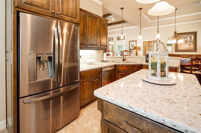 kitchen featuring light stone countertops, appliances with stainless steel finishes, backsplash, a tray ceiling, and decorative light fixtures