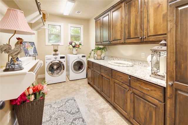 laundry room featuring washer and clothes dryer and cabinets