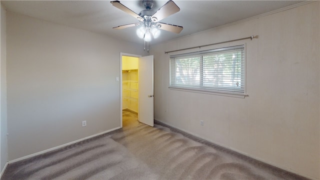 carpeted empty room with ceiling fan and ornamental molding